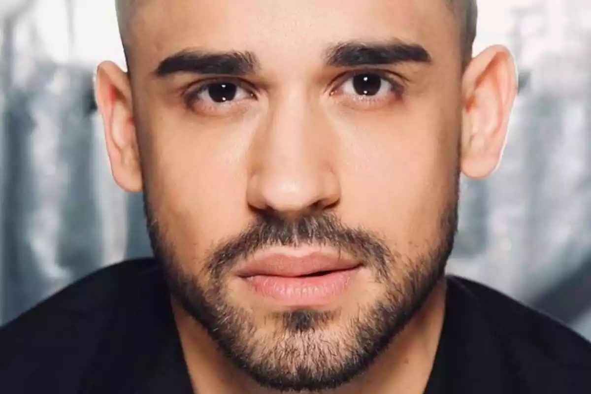 Un hombre con barba y cabello corto mirando hacia la cámara.